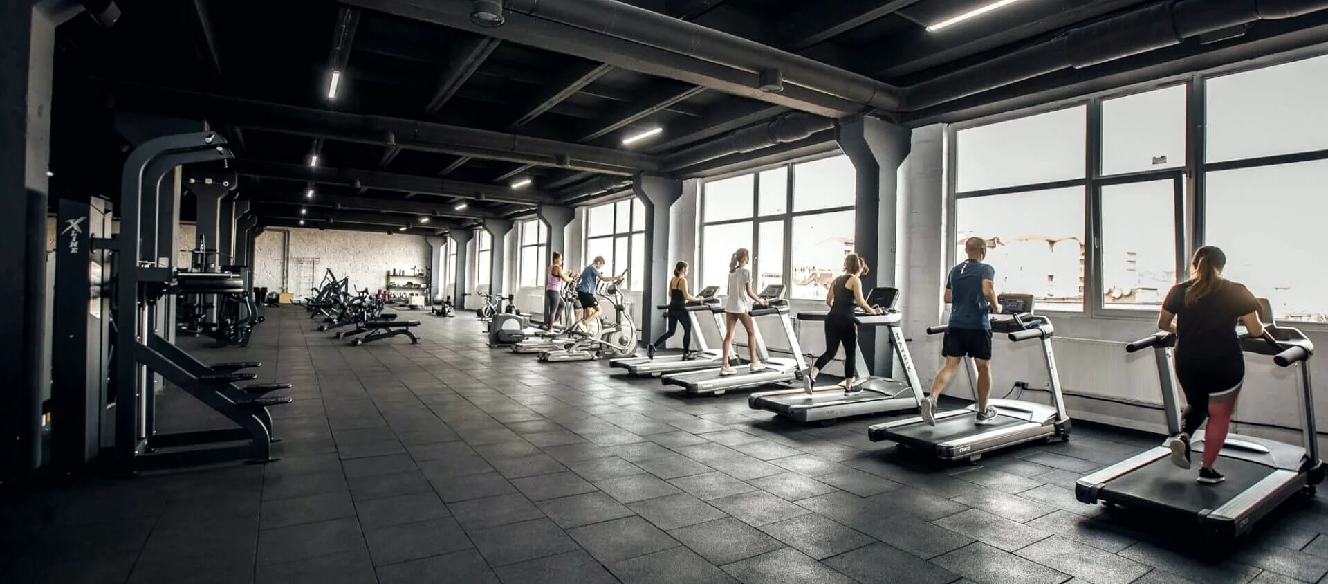 Кардіо-зона FitMe з панорамними вікнами та людьми на бігових доріжках